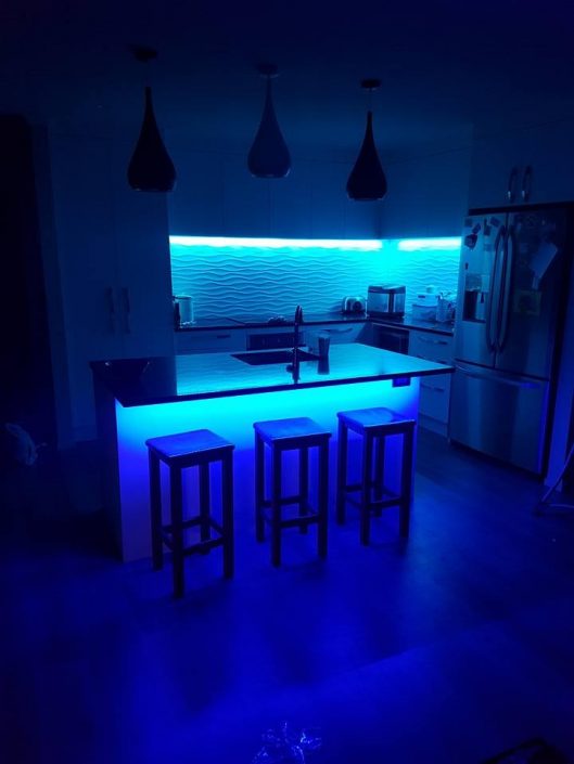 Blue lit kitchen with backlight on wall